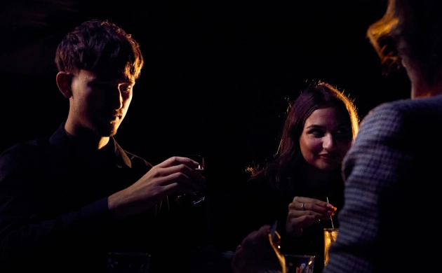 Un couple attablé, dégustant un cocktail dans l’obscurité totale