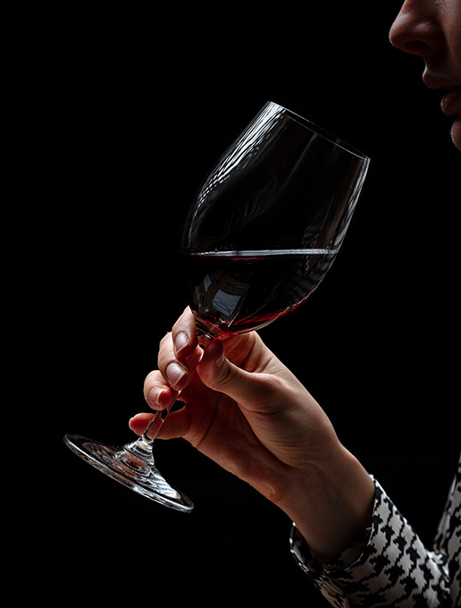A young woman savoring a glass of wine in a cozy atmosphere to celebrate Christmas at Dans le Noir ? restaurant