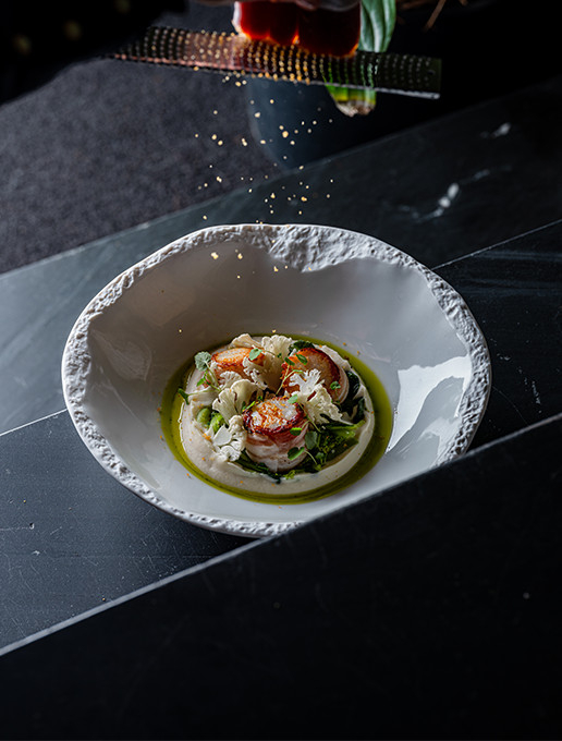 A refined scallop dish with an emulsion and crispy vegetables, served at Dans le Noir ? restaurant.