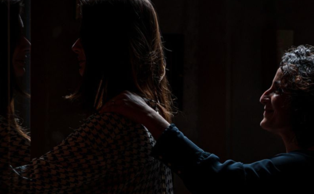 Deux femmes marchant en file indienne dans l’obscurité, souriantes et de profil, partageant un moment agréable